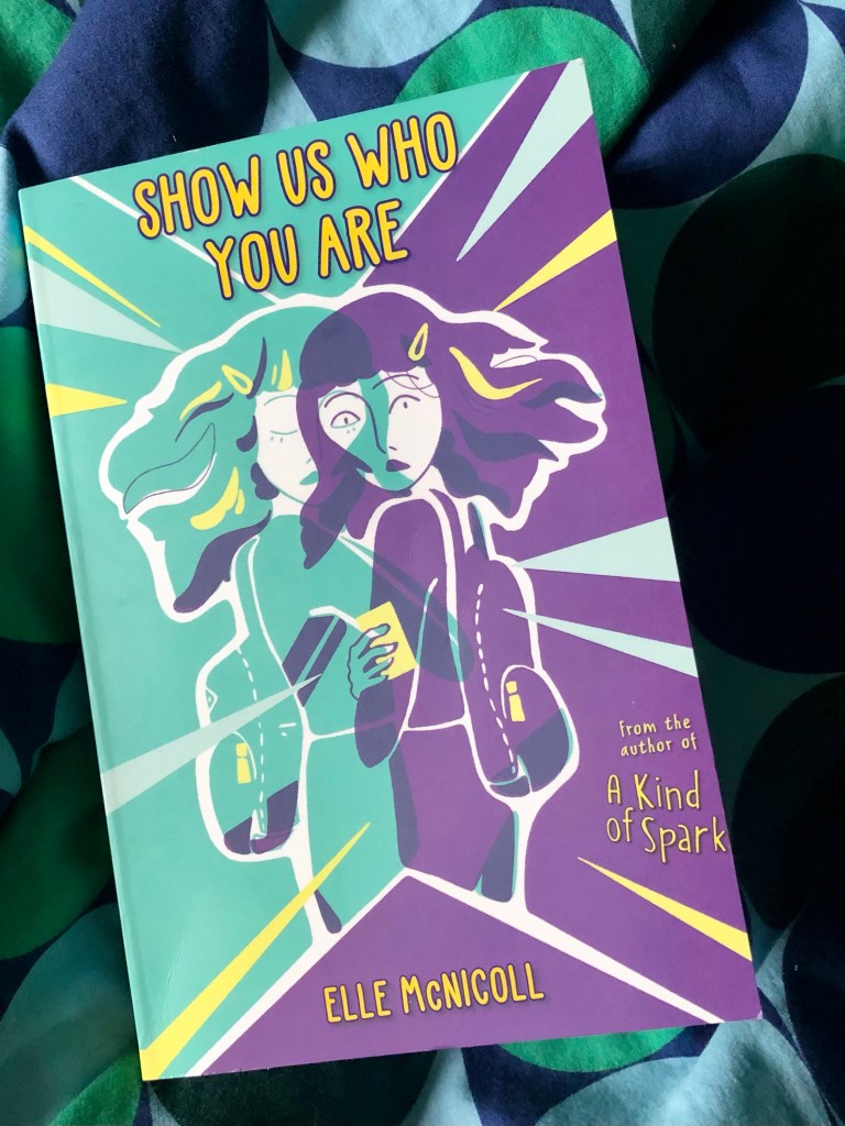 green and purply book cover with two images of a girl slightly overlapping, one with her eyes closed looking calm and the other eyes open looking shocked